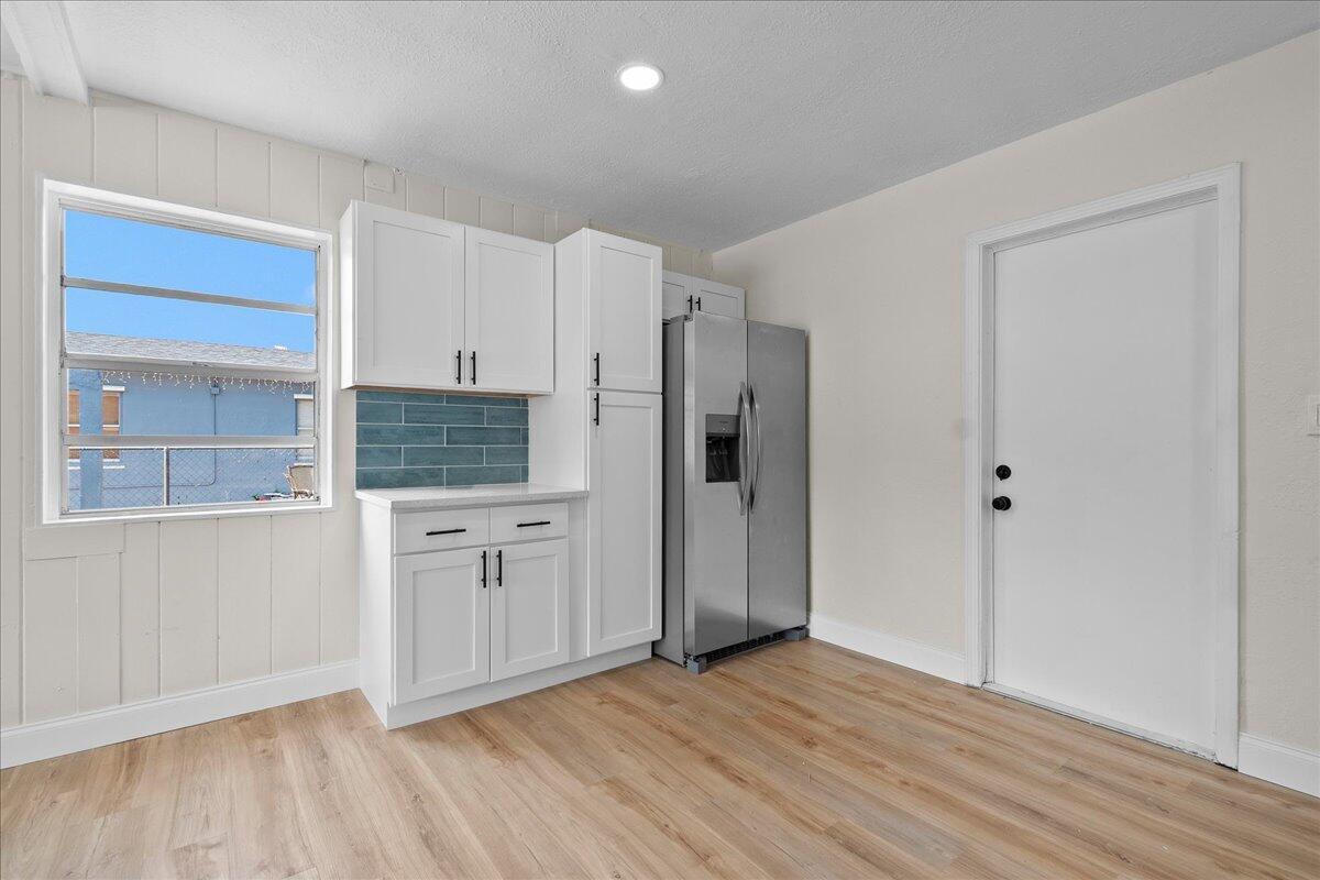 A kitchen features white cabinets, a blue tile backsplash, and a stainless steel refrigerator — 1306 S C Terrace, FL 33460, FL