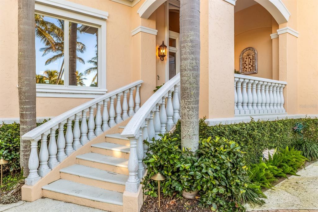 A peach-colored house exterior features a white balustrade staircase leading to a covered porch — 1640 JEAN LAFITTE DRIVE, BOCA GRANDE, FL
