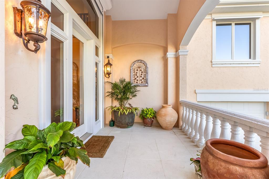 A covered balcony features light-colored tile flooring, potted plants, and a decorative wall accent — 1640 JEAN LAFITTE DRIVE, BOCA GRANDE, FL