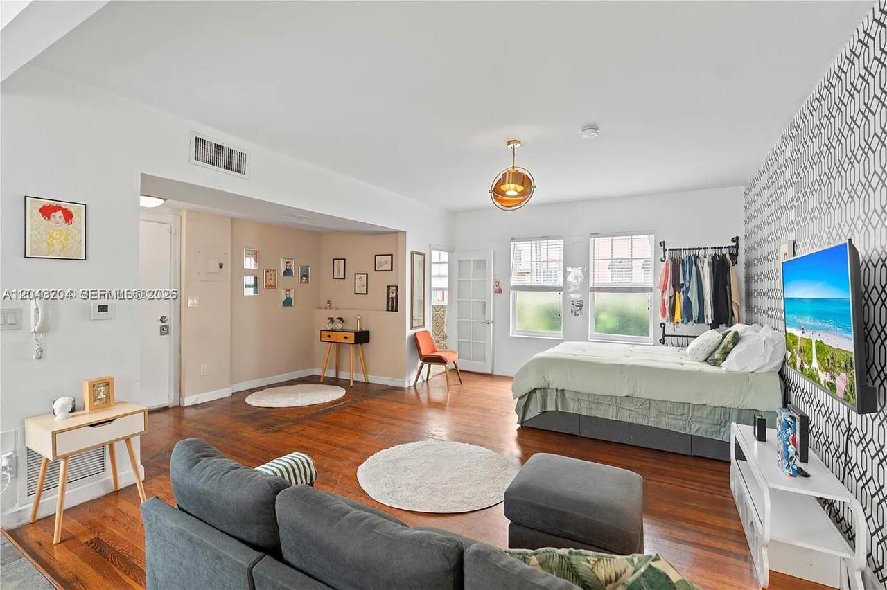 A studio apartment features hardwood floors, a bed, a sofa, and a patterned accent wall — 760 Meridian Ave # 3, Miami Beach FL 33139, MIAMI BEACH, FL