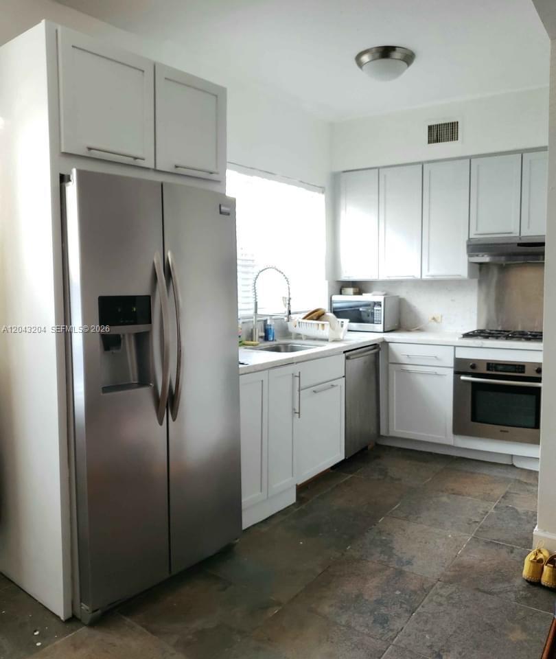 A kitchen features white cabinets, stainless steel appliances, and dark tiled flooring — 760 Meridian Ave # 3, Miami Beach FL 33139, MIAMI BEACH, FL