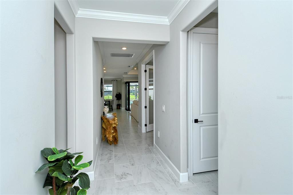 A hallway with light-colored tile flooring leads toward a living area with a glass door — 18114 WATERVILLE PLACE, BRADENTON, FL