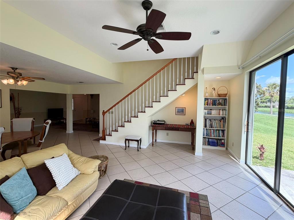 A living room features a staircase, a bookshelf, tile flooring, and a sliding glass door — 2570 SHADYBRANCH DRIVE, ORLANDO, FL
