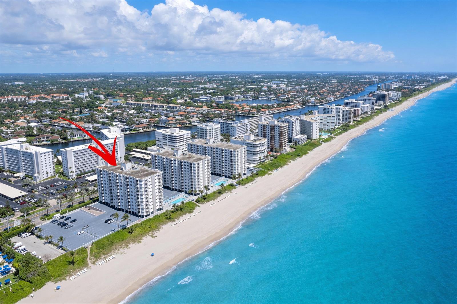 An aerial view shows a white high-rise condominium building situated directly on a sandy beach — 3301 S Ocean Boulevard # 109, Highland Beach FL 33487, HIGHLAND BEACH, FL