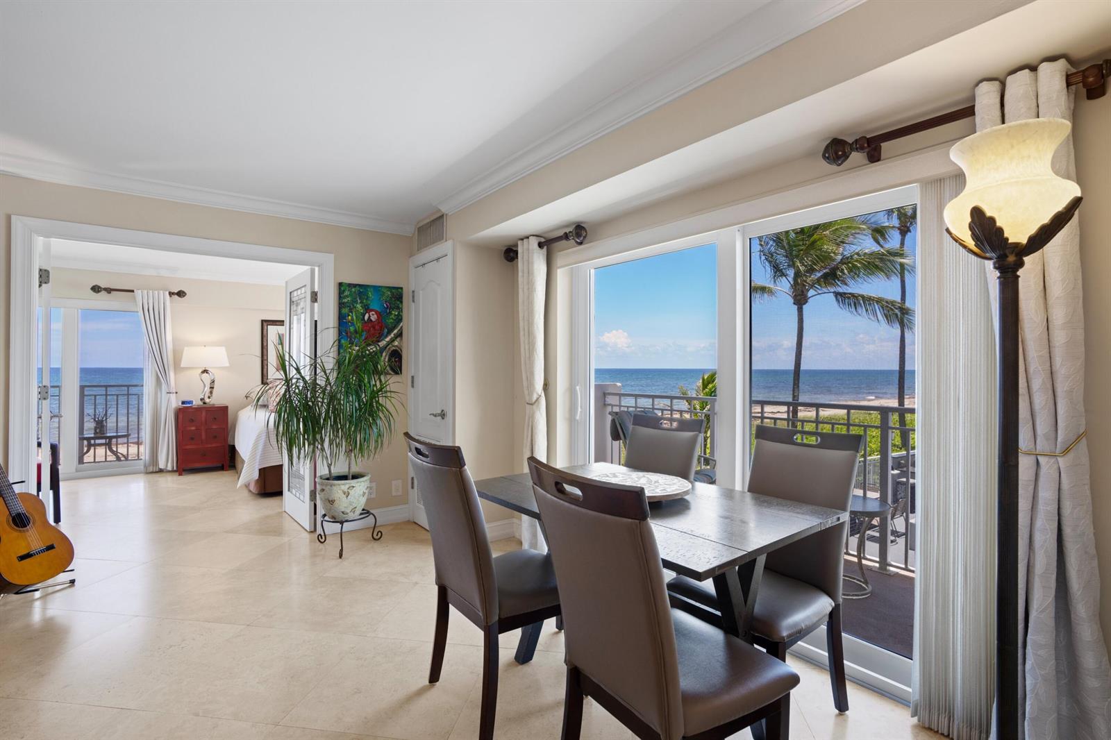 A dining area with a table and chairs overlooks a balcony with ocean views — 3301 S Ocean Boulevard # 109, Highland Beach FL 33487, HIGHLAND BEACH, FL
