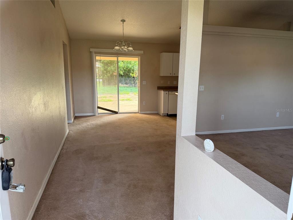 A carpeted living area leads to a kitchen and a sliding glass door to the backyard — 19 PECAN PASS TERRACE, OCALA, FL