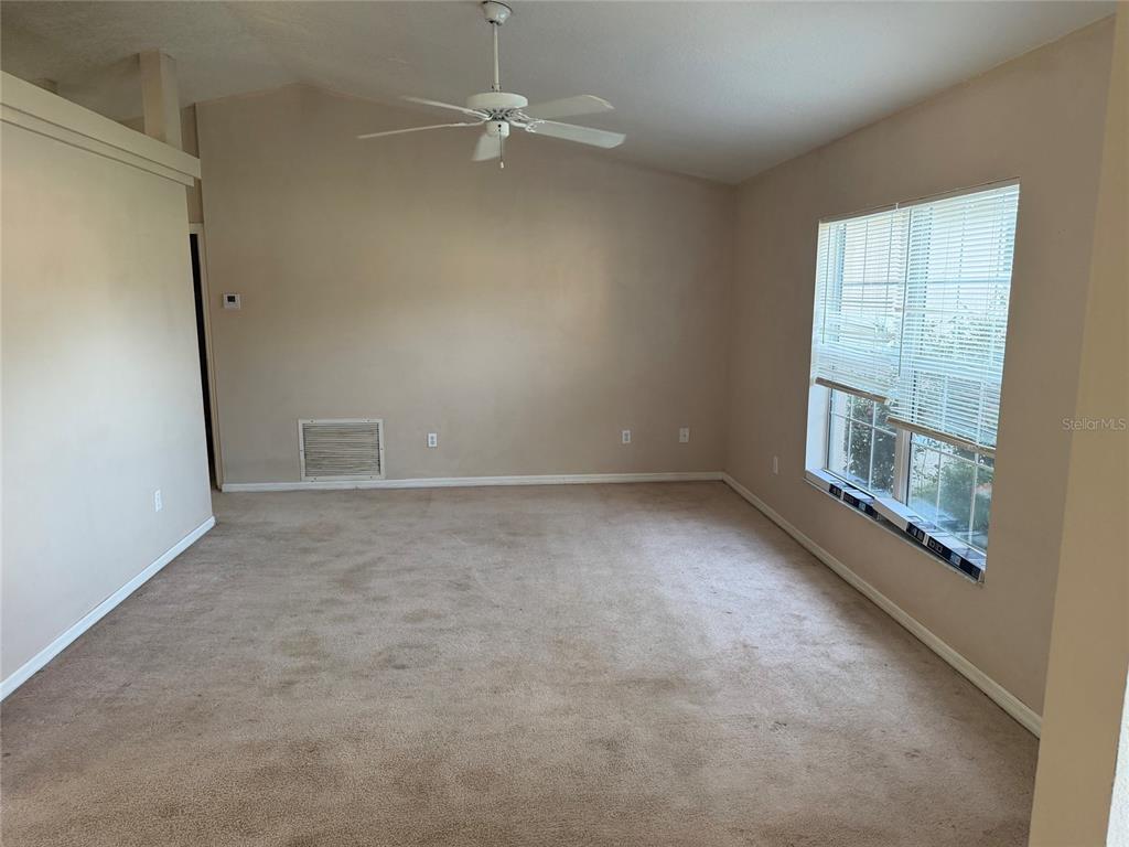 A kitchen features white cabinets, laminate countertops, and tile flooring, opening to a carpeted room — 19 PECAN PASS TERRACE, OCALA, FL