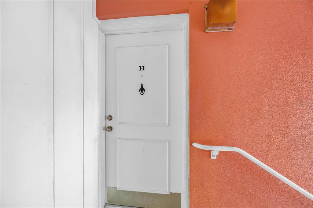 A white door marked with an H is set into a bright orange exterior wall — 3795 41ST LANE S UNIT H, ST PETERSBURG, FL