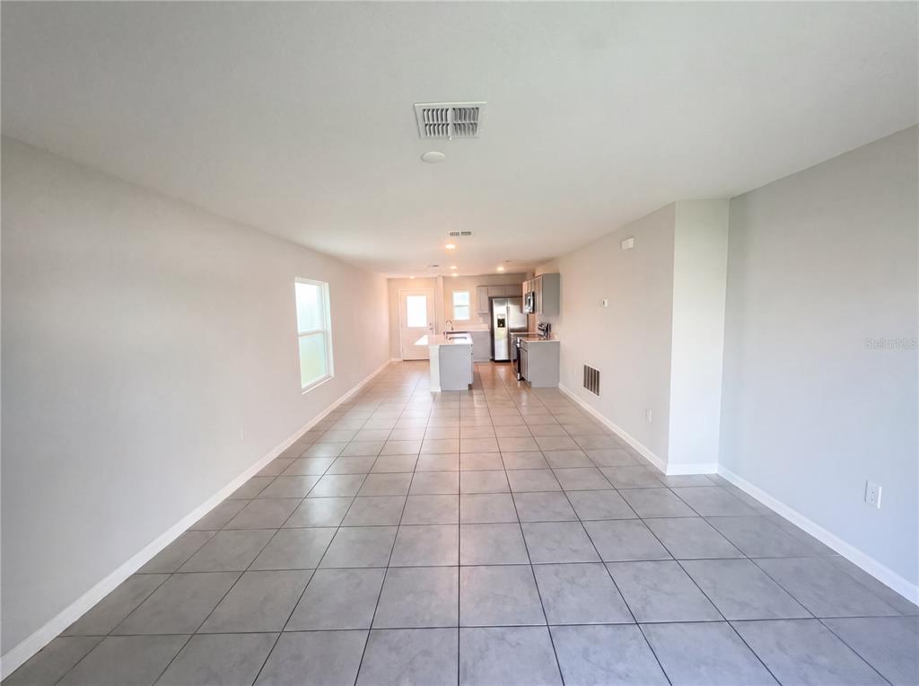 An open-concept living area features light gray tile flooring, neutral walls, and a kitchen — 4322 SUNNY CREEK PLACE, KISSIMMEE, FL