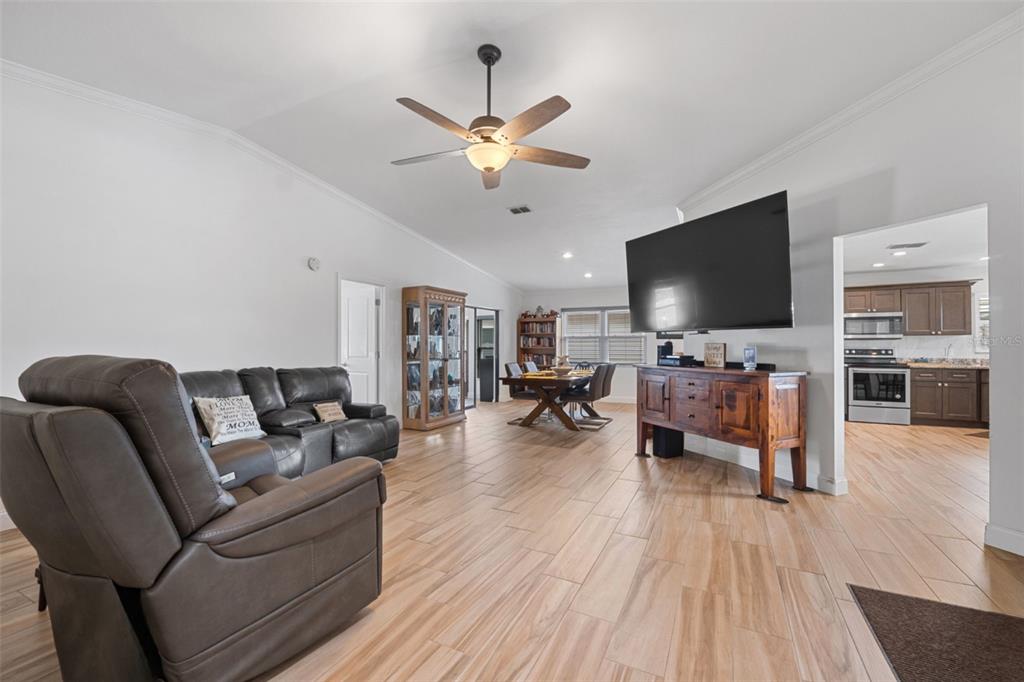 A living room with wood-look tile flooring, a ceiling fan, and an open dining area — 1957 PRAIRIE DUNES CIRCLE N, LAKELAND, FL