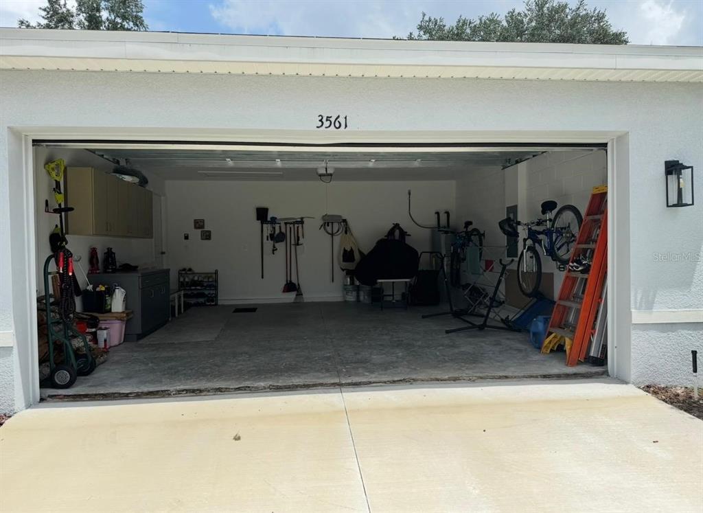 An open two-car garage with concrete floors, storage cabinets, and various tools and equipment — 3561 SW 150TH LOOP, OCALA, FL
