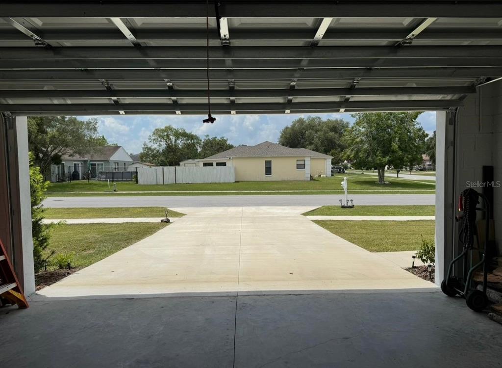 View from inside a garage looking out onto a concrete driveway and a suburban street — 3561 SW 150TH LOOP, OCALA, FL