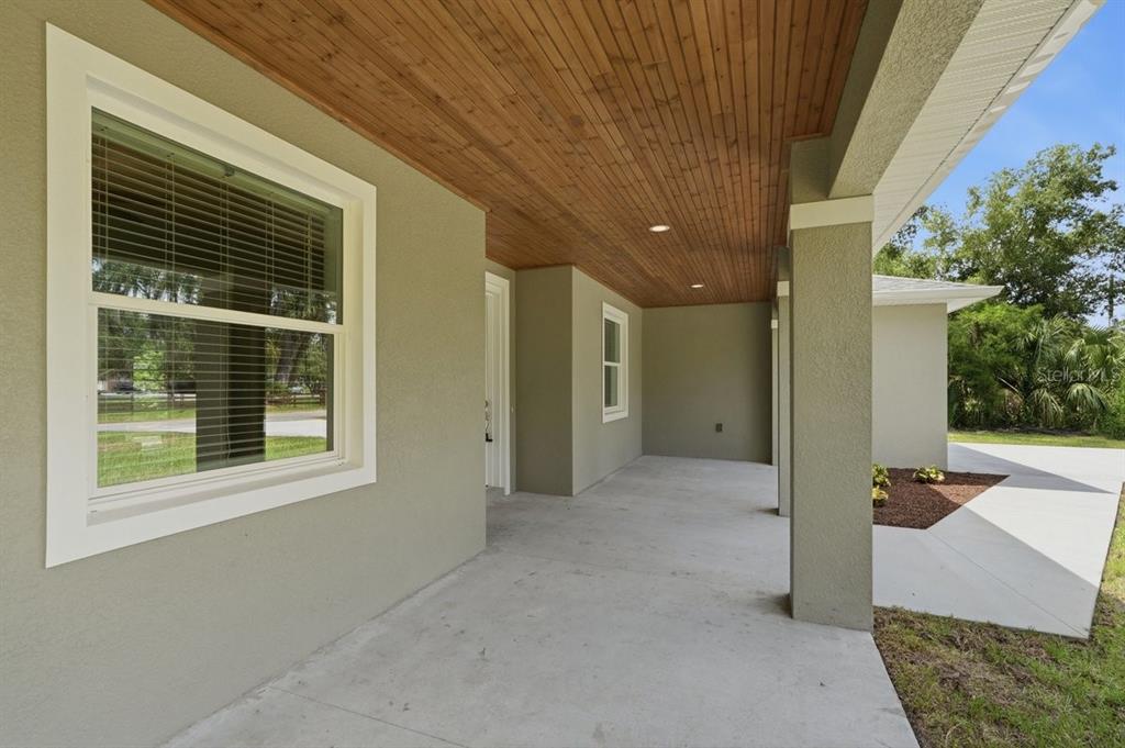 A covered concrete porch features a wood-paneled ceiling, recessed lighting, and light-colored exterior walls — 2030 HONTOON ROAD, DELAND, FL