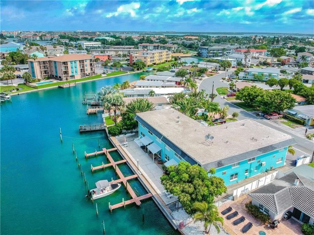 An aerial view of a teal waterfront apartment building with private boat docks and parking — 11440 1ST STREET E UNIT 1, TREASURE ISLAND, FL