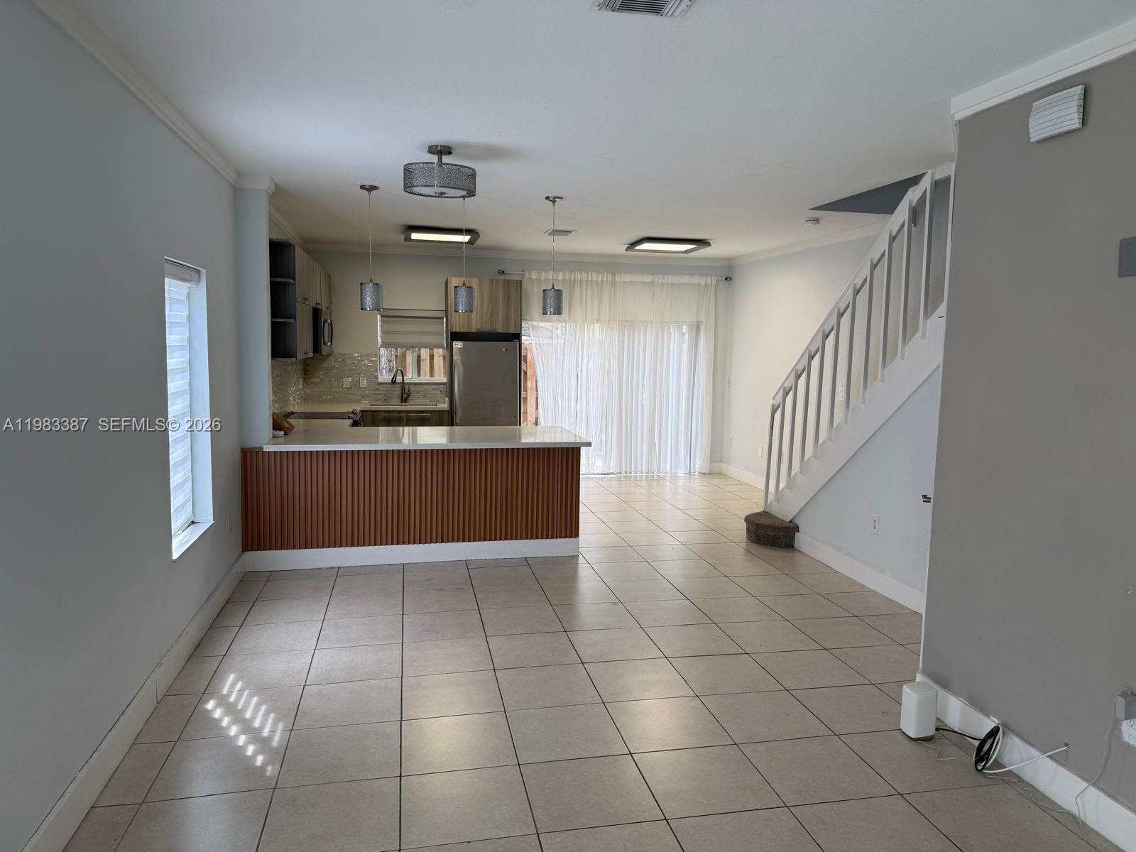 An open-concept kitchen with a wood-paneled island, tile flooring, and a staircase to the right — 10776 NW 83rd Ter # 19, Doral FL 33178, DORAL, FL