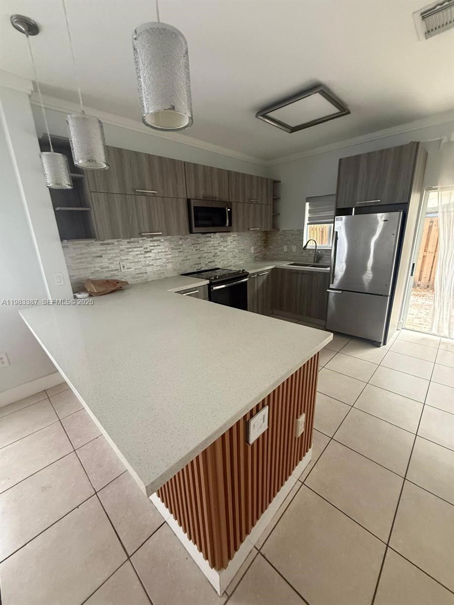 A modern kitchen features light wood cabinets, stainless steel appliances, and a white quartz island — 10776 NW 83rd Ter # 19, Doral FL 33178, DORAL, FL