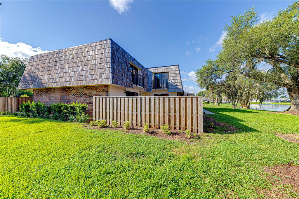 A two-story building with a mansard roof and a wooden privacy fence on a lawn — 921 ROYAL OAK BOULEVARD, LEESBURG, FL