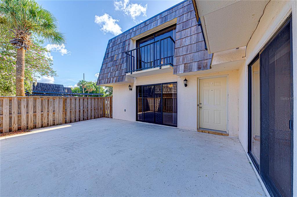 A concrete patio sits outside a two-story building with a wooden shingled mansard roof — 921 ROYAL OAK BOULEVARD, LEESBURG, FL