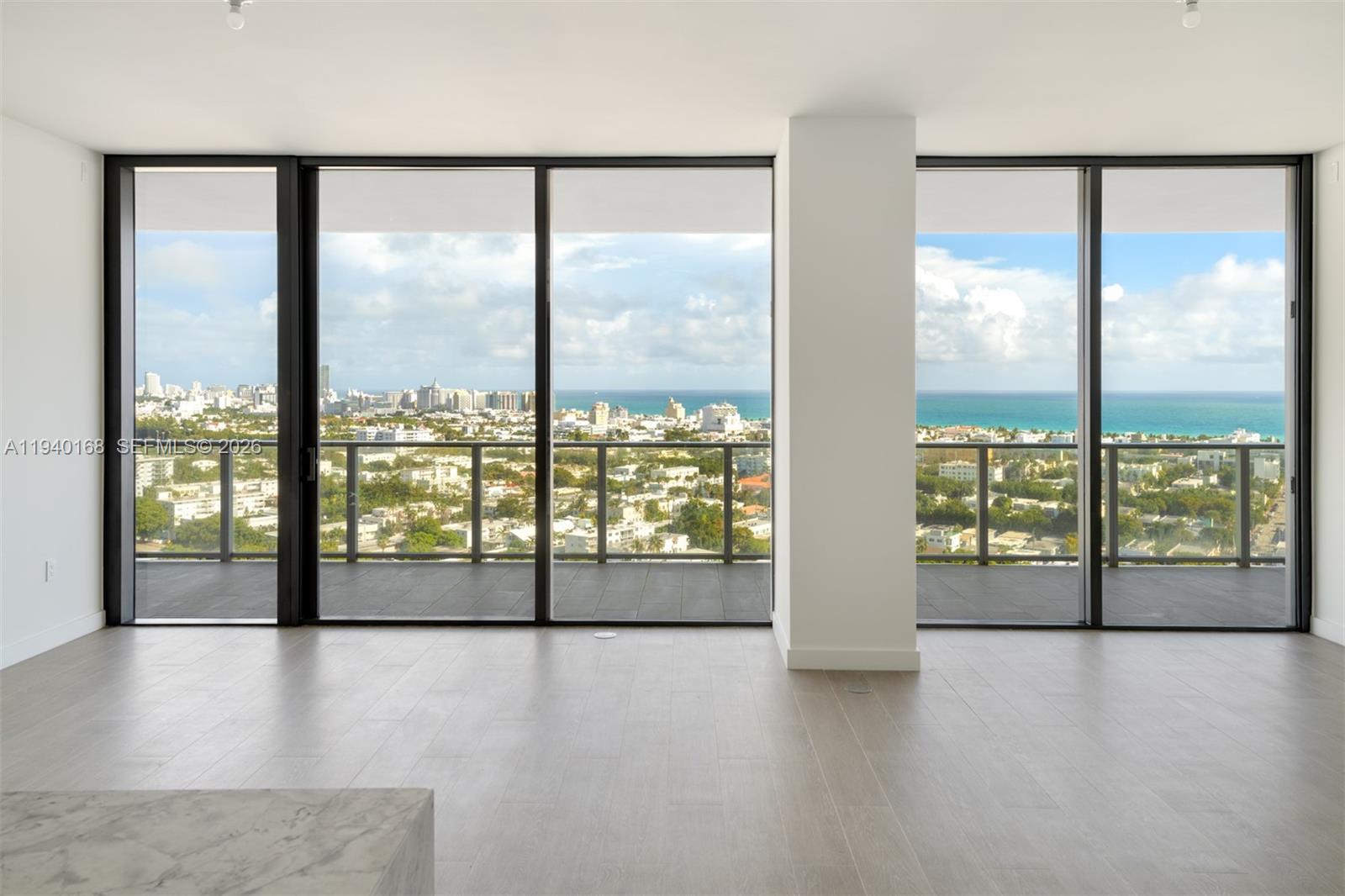 An empty room features light wood-look flooring, floor-to-ceiling windows, and a balcony with ocean views — 500 Alton Rd # 2207, Miami Beach FL 33139, MIAMI BEACH, FL