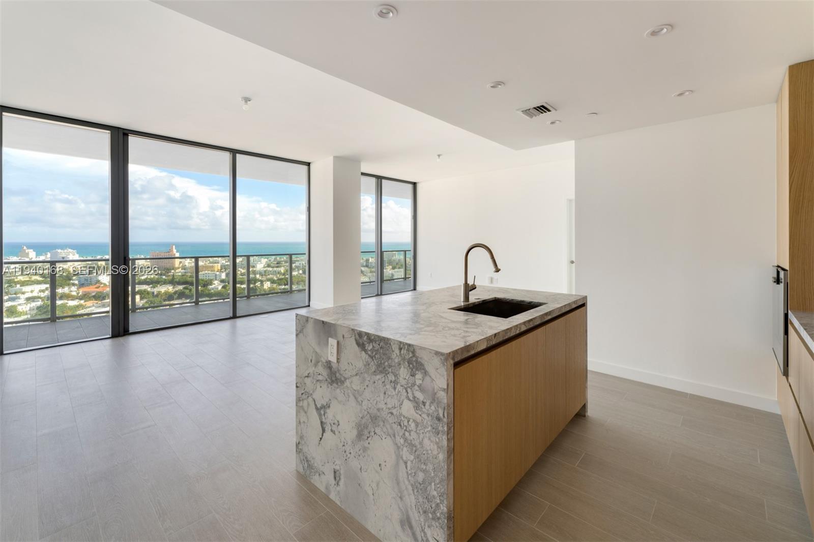 A modern kitchen island with marble countertops sits in an open room with floor-to-ceiling windows — 500 Alton Rd # 2207, Miami Beach FL 33139, MIAMI BEACH, FL