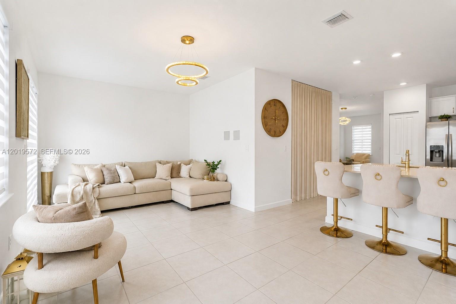 A living room with a beige sectional sofa, a round chair, and a kitchen island — 12954 SW 231st St, Miami FL 33170, MIAMI, FL