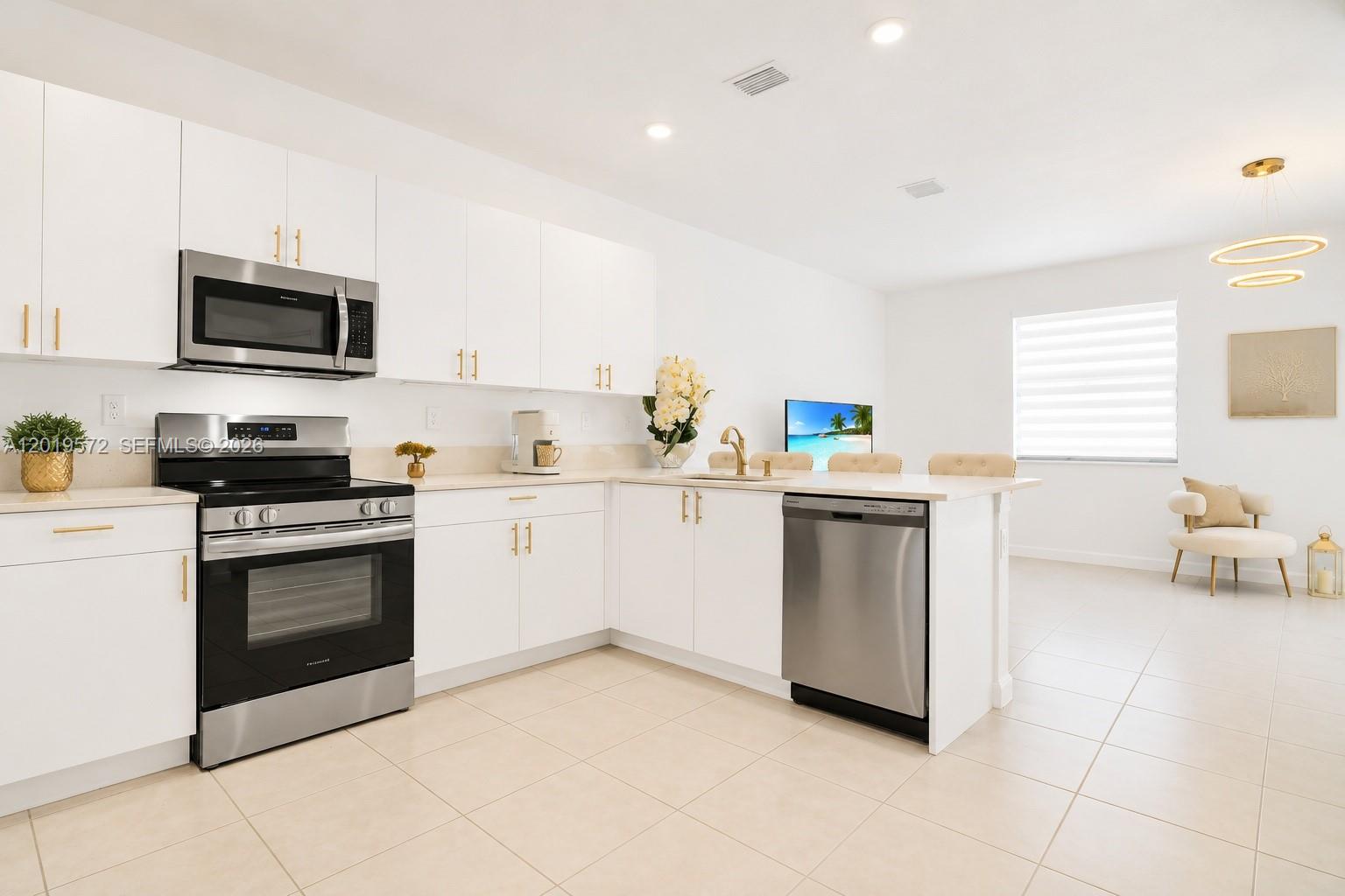 A modern kitchen features white cabinets, stainless steel appliances, and a peninsula with a sink — 12954 SW 231st St, Miami FL 33170, MIAMI, FL
