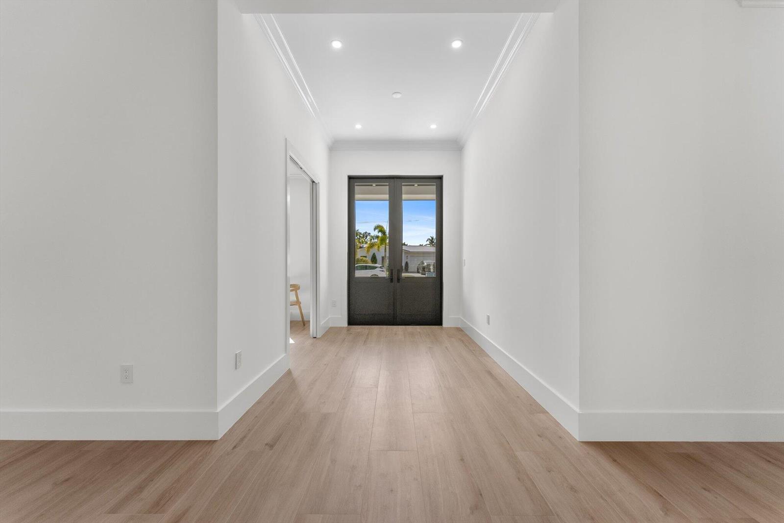 A bright entryway features light wood flooring, white walls, and a dark double-door entrance — 715 Mission Hill Road, Boynton Beach FL 33435, BOYNTON BEACH, FL