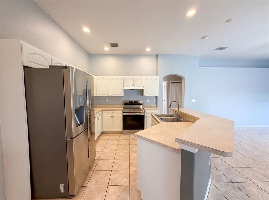A kitchen features white cabinets, stainless steel appliances, a tiled floor, and a breakfast bar — 222 TAYLOR BAY LANE, BRANDON, FL