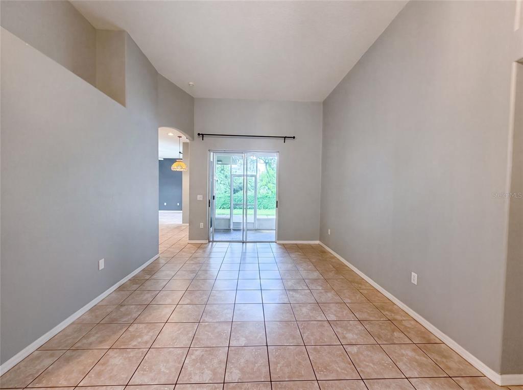 A room with high ceilings, tile flooring, and a sliding glass door leading to a patio — 222 TAYLOR BAY LANE, BRANDON, FL