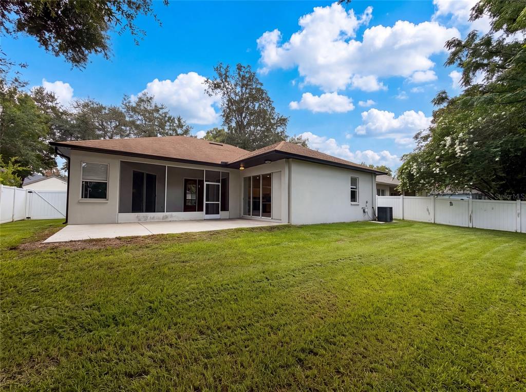 The backyard features a concrete patio, a screened-in porch, and a white vinyl fence — 222 TAYLOR BAY LANE, BRANDON, FL