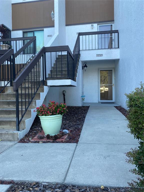 A concrete walkway leads to the entrance of a multi-level residential building with stairs — 4400 CASTLEPALM ROAD, ORLANDO, FL