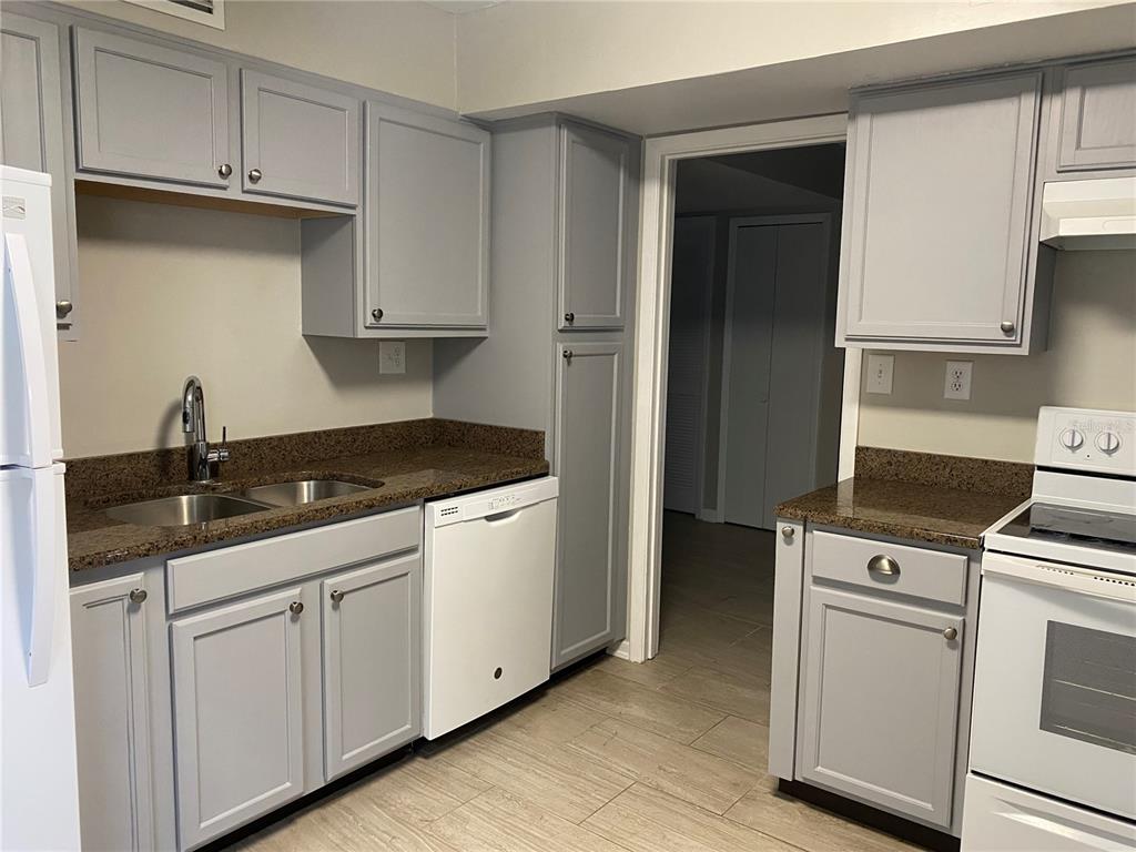 A kitchen features gray cabinets, brown granite countertops, white appliances, and light-colored tile flooring — 4400 CASTLEPALM ROAD, ORLANDO, FL