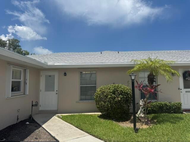A beige single-story house exterior features a white front door, a window, and landscaping — 542 Franconia Circle, Lake Worth FL 33467, LAKE WORTH, FL