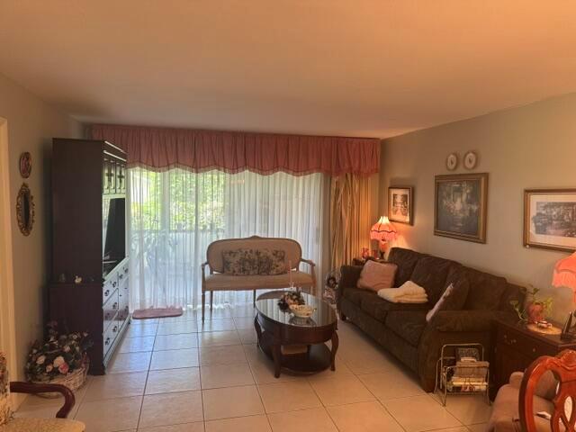A living room features tile flooring, a dark sofa, a loveseat, and a large window — 542 Franconia Circle, Lake Worth FL 33467, LAKE WORTH, FL