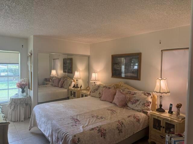 A bedroom features a floral bedspread, mirrored closet doors, two nightstands with lamps, and tile flooring — 542 Franconia Circle, Lake Worth FL 33467, LAKE WORTH, FL