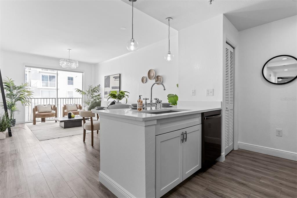 A modern kitchen island with a sink overlooks a bright living room with balcony access — 700 S HARBOUR ISLAND BOULEVARD UNIT 647, TAMPA, FL