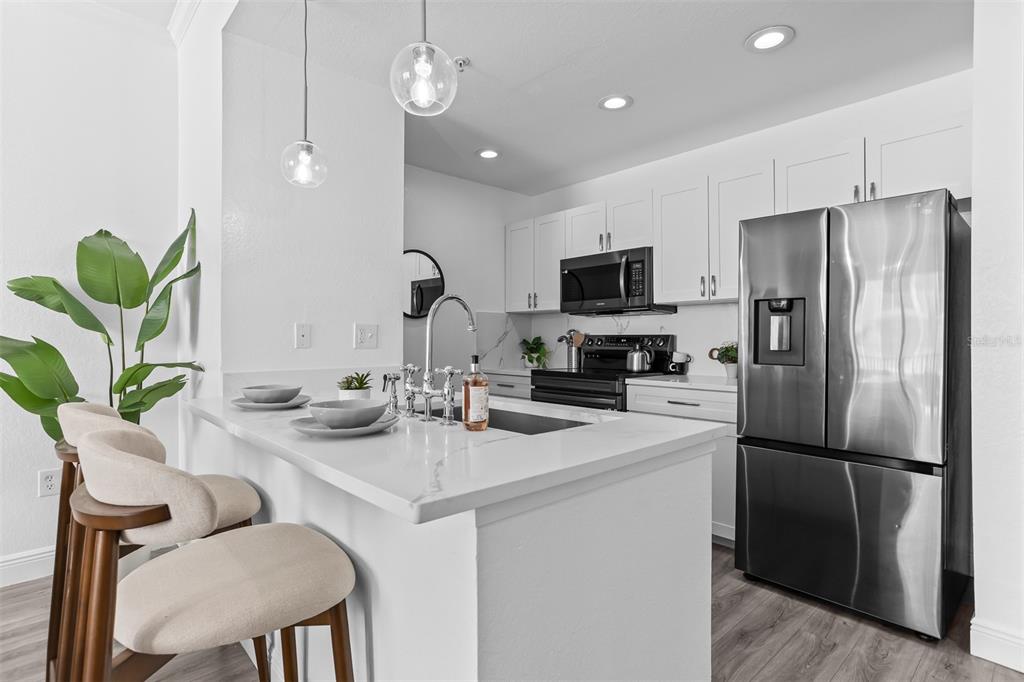 A modern kitchen features white cabinetry, stainless steel appliances, and a quartz-topped island with seating — 700 S HARBOUR ISLAND BOULEVARD UNIT 647, TAMPA, FL