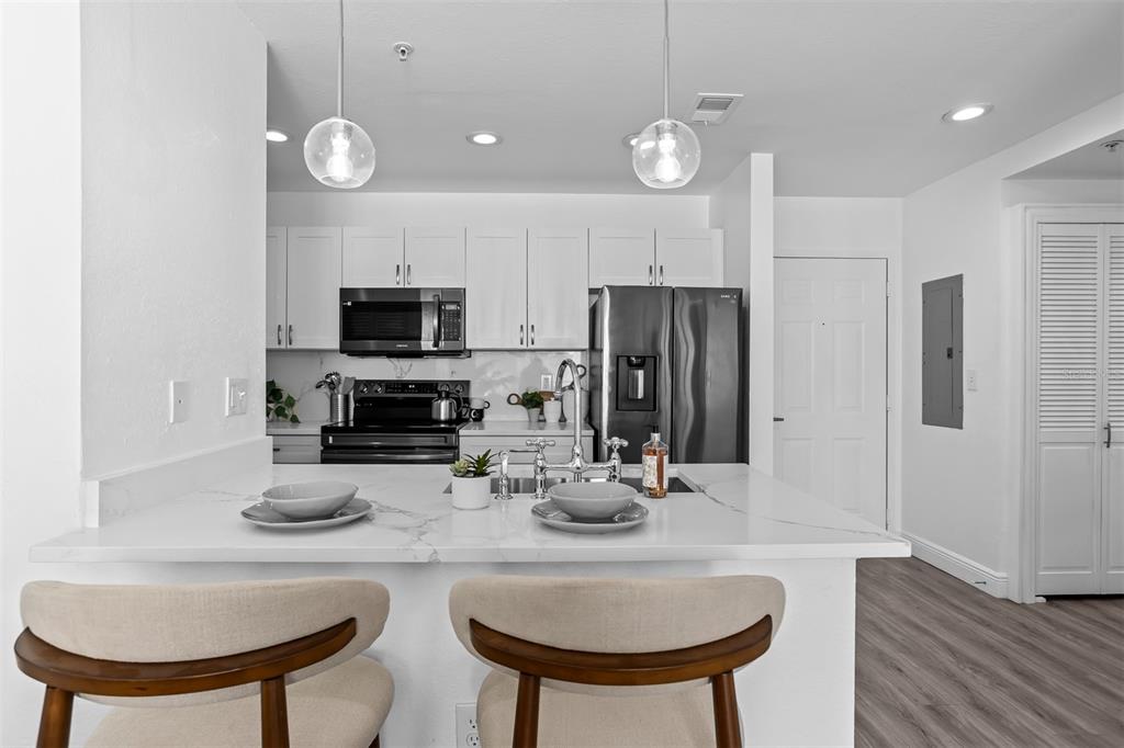 A modern kitchen features white cabinets, stainless steel appliances, and a marble-topped island with seating — 700 S HARBOUR ISLAND BOULEVARD UNIT 647, TAMPA, FL
