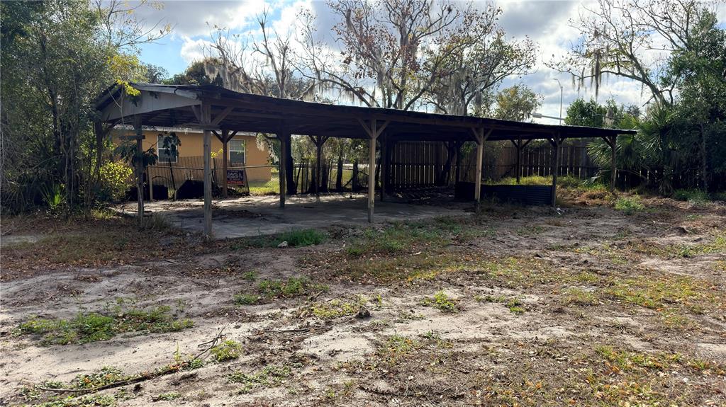 A large, open-sided wooden carport stands on a concrete slab in a grassy lot — 11 7TH STREET SE, FORT MEADE, FL