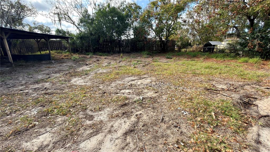 A large, sandy, partially grassy backyard features a wooden pavilion and a small shed — 11 7TH STREET SE, FORT MEADE, FL