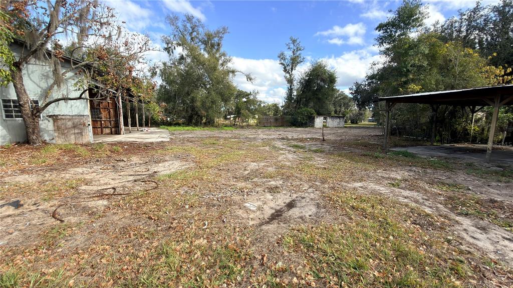 An outdoor view of a dirt lot with a metal shed and a covered carport — 11 7TH STREET SE, FORT MEADE, FL