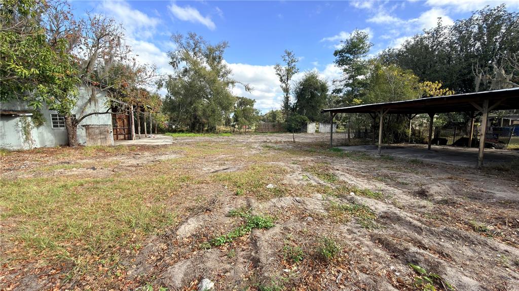 A dirt lot features a small shed on the left and a covered carport structure — 11 7TH STREET SE, FORT MEADE, FL