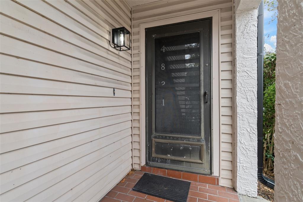 A front entryway features a dark screen door with house numbers on a tiled porch — 4821 PURITAN CIRCLE UNIT 104, TAMPA, FL