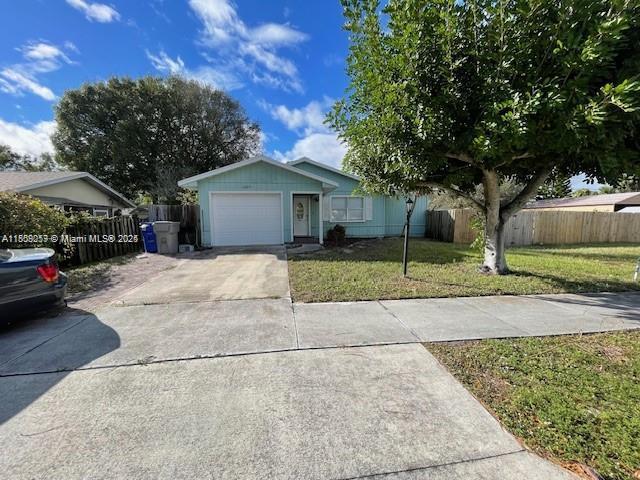 A light blue single-story house with a garage and a large tree in the front yard — 1685 20th Ave SW, Vero Beach FL 32962, VERO BEACH, FL