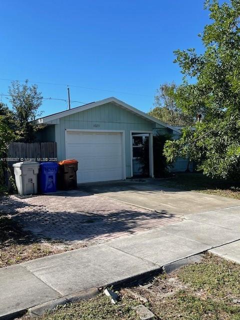 A single-story house with a white garage door and two trash bins on a driveway — 1685 20th Ave SW, Vero Beach FL 32962, VERO BEACH, FL