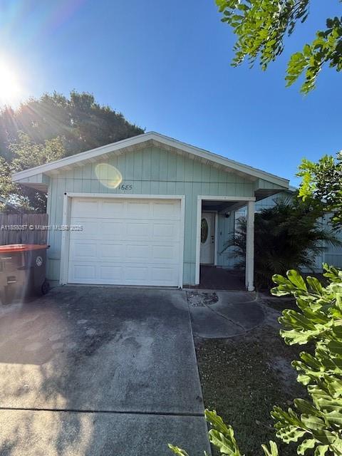 A light green house features a white garage door and an adjacent front entrance — 1685 20th Ave SW, Vero Beach FL 32962, VERO BEACH, FL