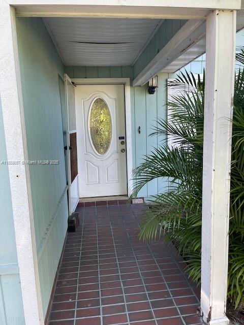 A covered entryway features a white front door with an oval window and tiled flooring — 1685 20th Ave SW, Vero Beach FL 32962, VERO BEACH, FL