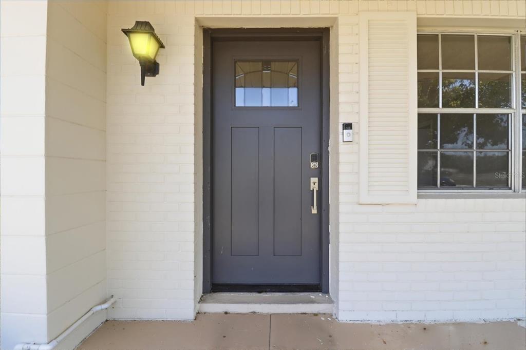 A dark gray front door with a window sits in a white brick exterior wall — 5188 WOODRIDGE LANE, SPRING HILL, FL
