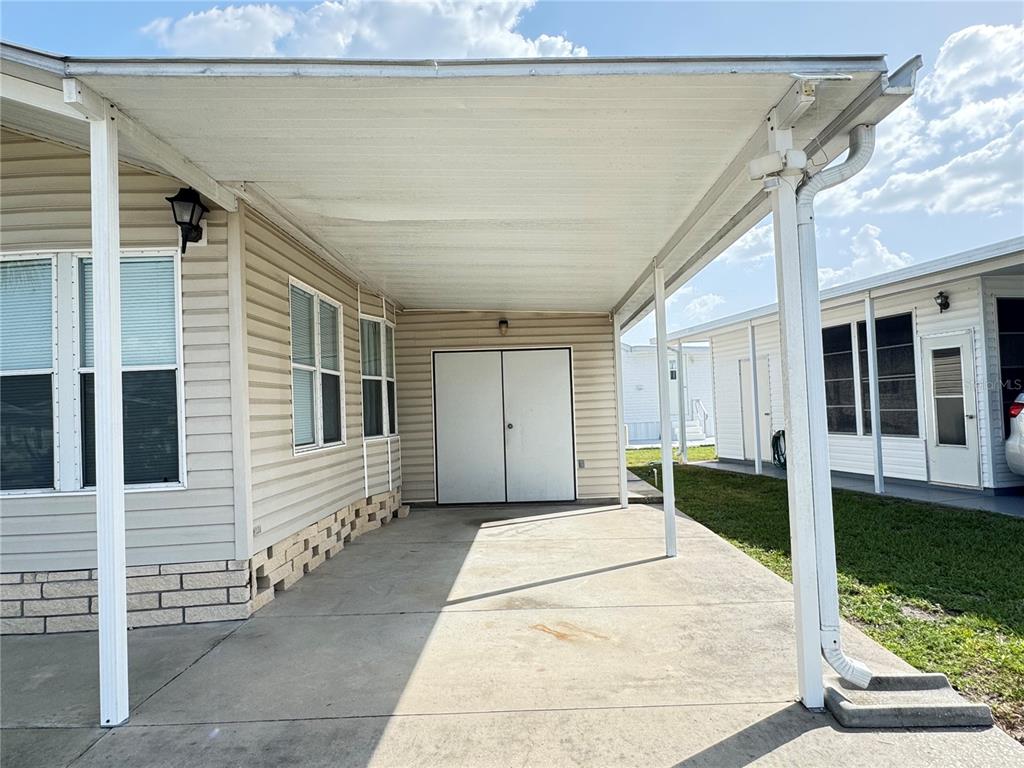 A concrete carport with a white metal roof and a storage shed at the end — 35114 GARBER LANE, ZEPHYRHILLS, FL