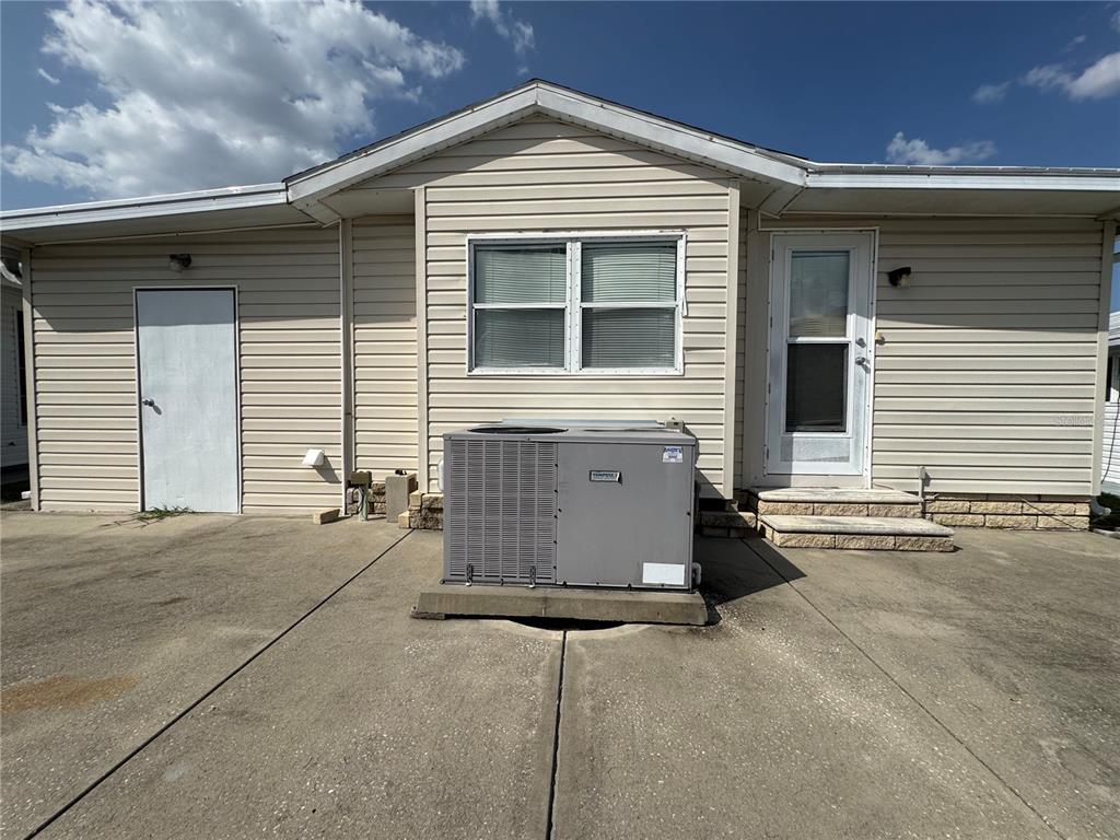 The exterior of a beige house features a central air conditioning unit on a concrete patio — 35114 GARBER LANE, ZEPHYRHILLS, FL